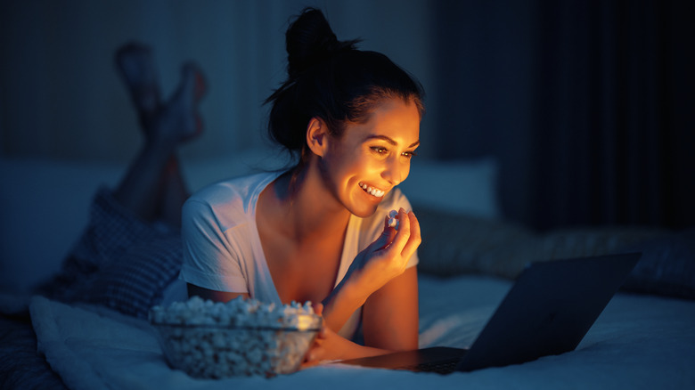 A woman eats in bed