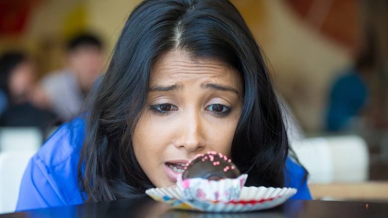 woman looking longingly at a piece of chocolate covered candy