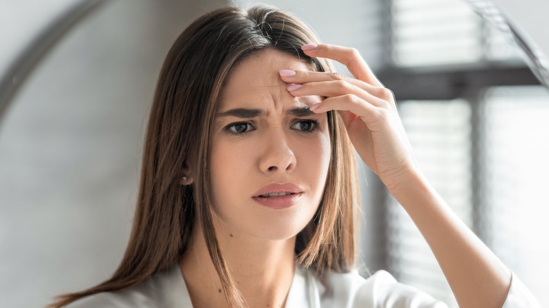 woman looking worried in the mirror at wrinkle