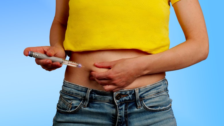 person giving themselves an insulin shot indicating diabetes
