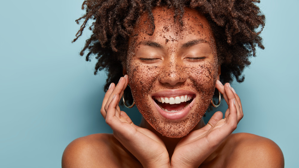 Woman smiling with eyes closed while wearing facial scrub