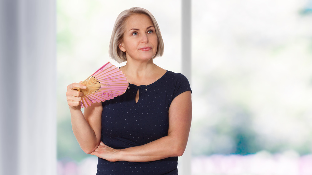 Middle-aged woman standing fanning herself