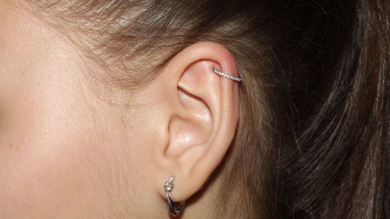 an earlobe and cartilage piercing on white woman's ear