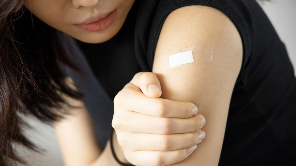 Young woman holding her arm in pain after receiving a vaccination 