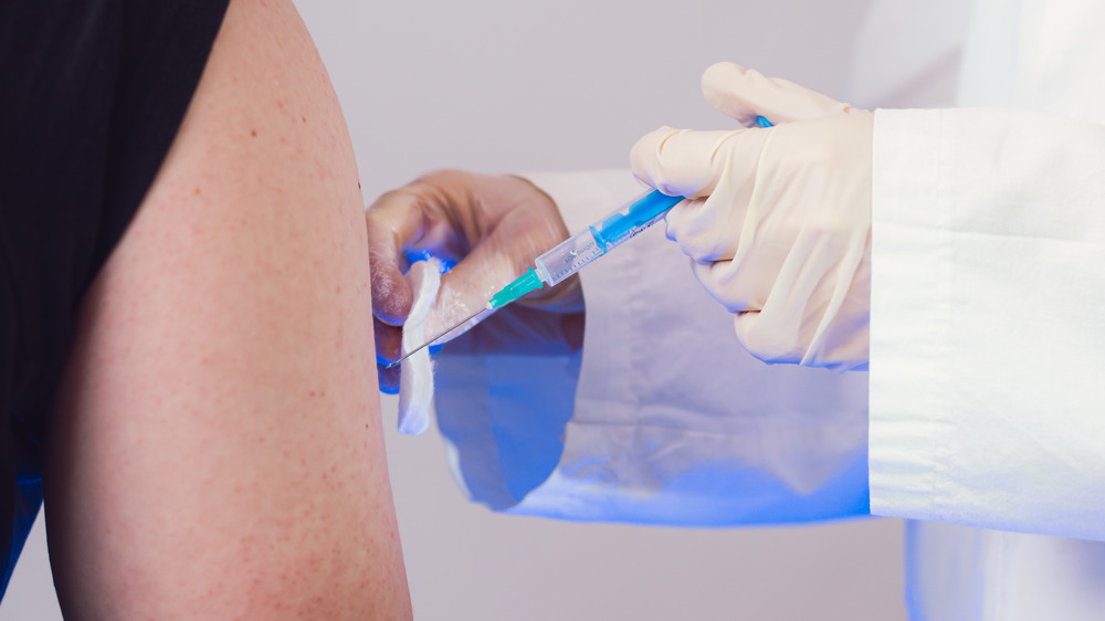 Close up of a vaccine being administered into a freckled arm