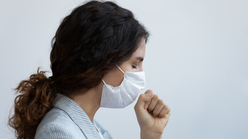 A masked woman coughing 