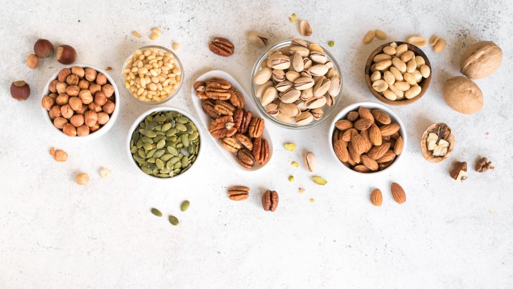 Nuts and seeds in bowls on grey background