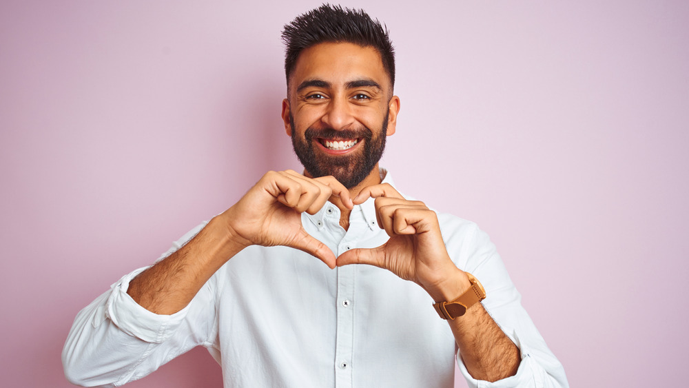 smiling man doing heart sign with hands