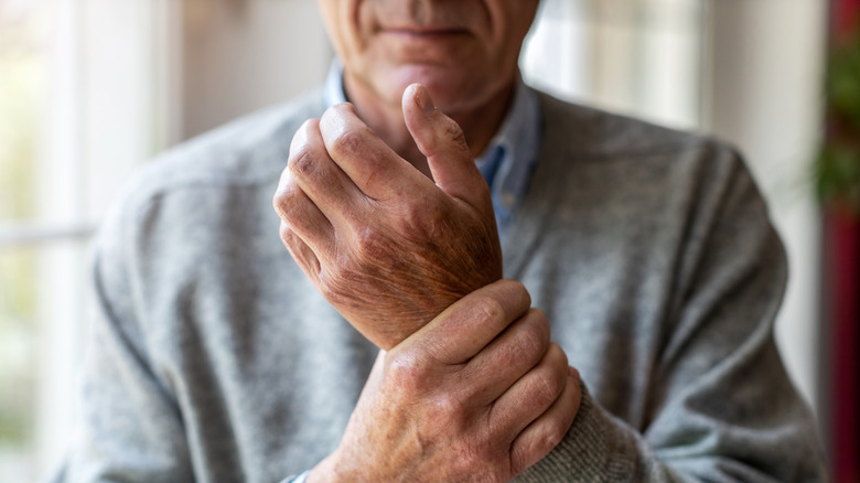 man in sweater holding wrist