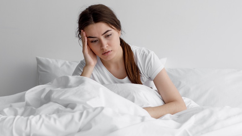 woman in bed with headache holding head