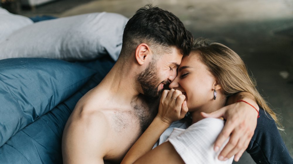 A happy couple in bed together, pressing their foreheads together