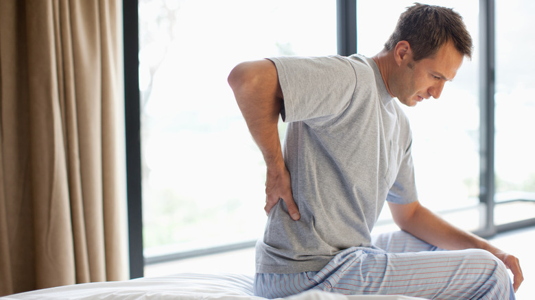 Man sitting on bed with back pain