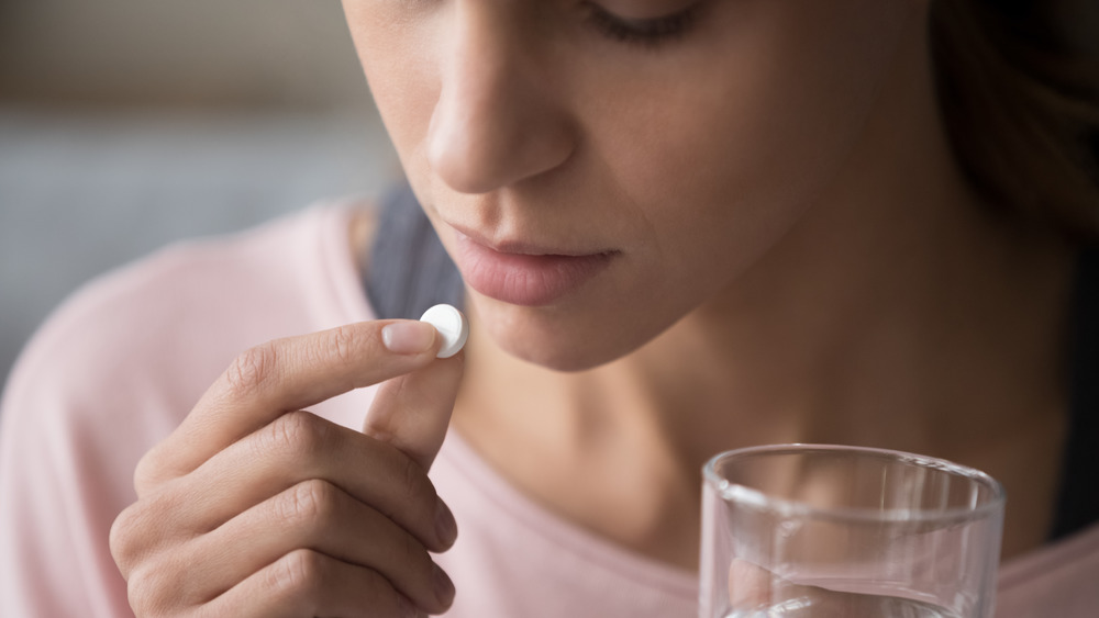 Person holding pill and glass of water