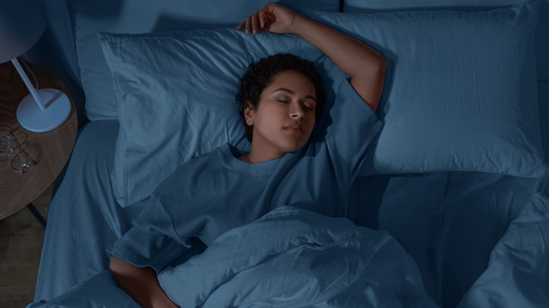 Woman sleeps comfortably on her back in bed