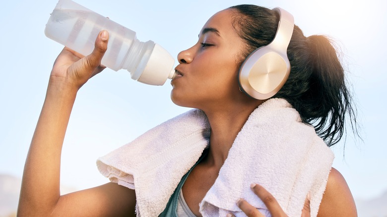 woman cooling down and drinking water after workout