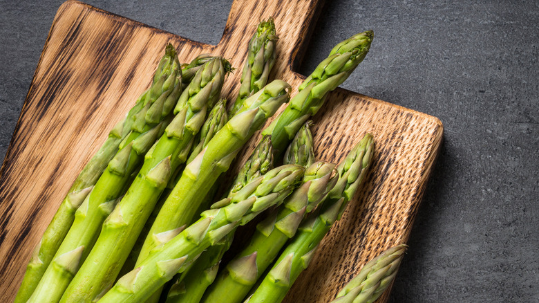 Asparagus stalks on wooden cutting board