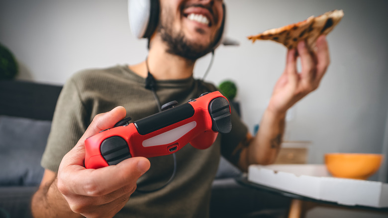 person eating pizza and gaming