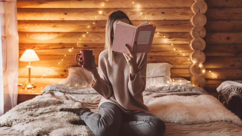 young woman relaxing and reading a book on bed 