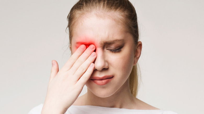 A young woman experiencing pain in her left eye 