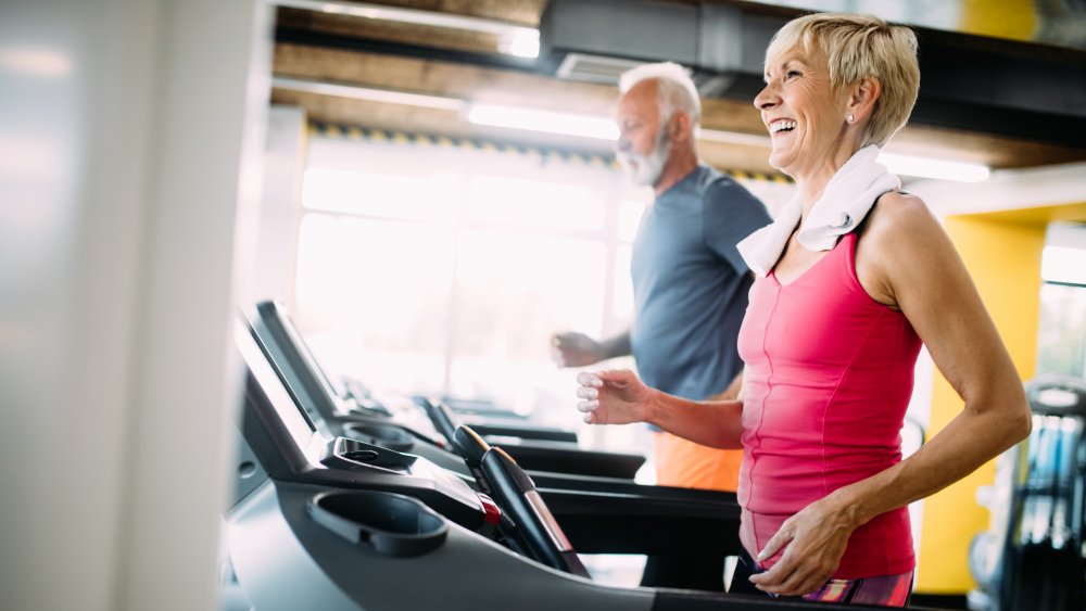 Two older adults on treadmills