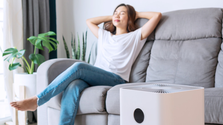 Woman sitting on couch near air purifier 