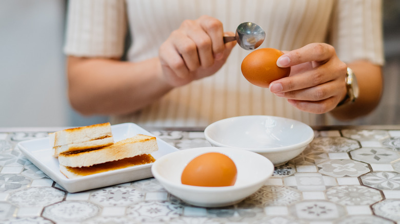 woman's hand cracking a hard-boiled egg