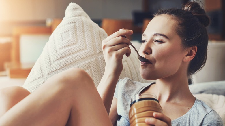 Woman smiling while eating a spoonful of peanut butter