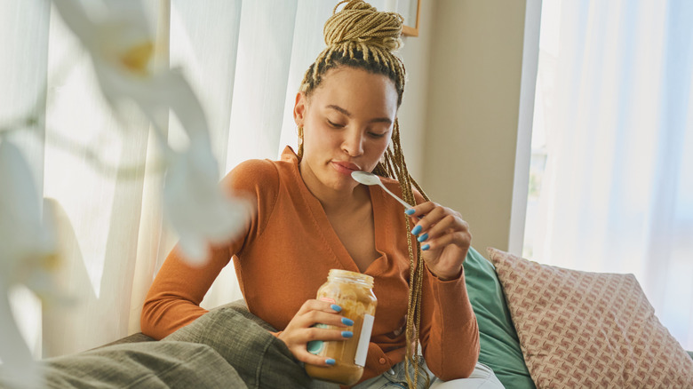 Woman sitting on her couch eating peanut butter