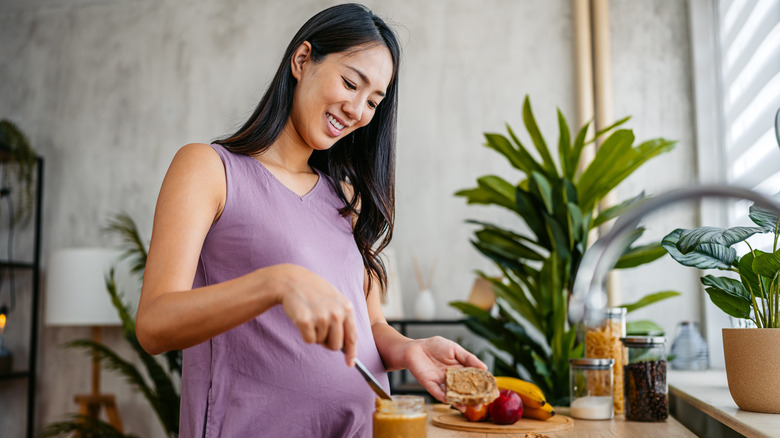 Pregnant woman preparing a peanut butter sandwich