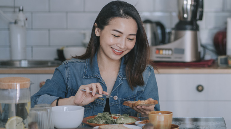 Smiling woman spreading peanut butter on bread