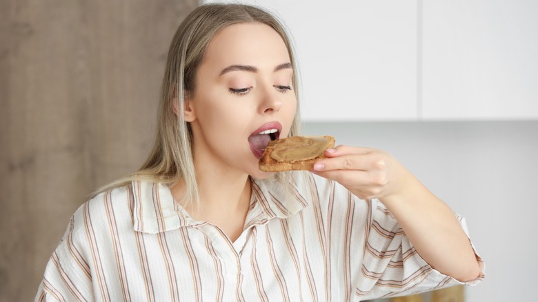 Woman eating a slice of toast with peanut butter