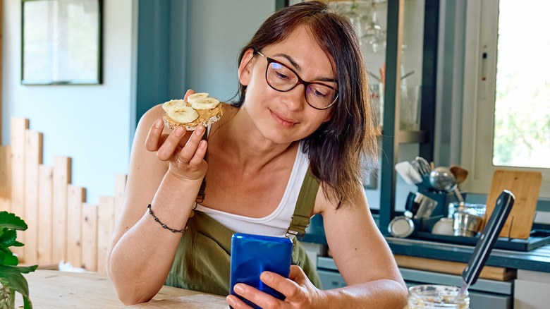 Woman eating a rice cake topped with peanut butte