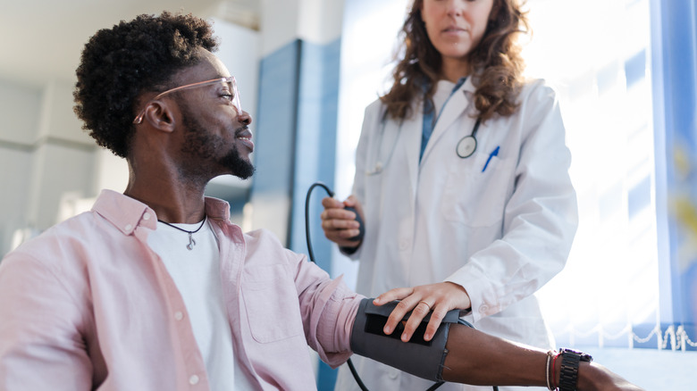 Doctor checking man's blood pressure