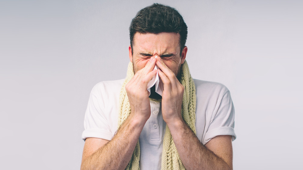 man sneezing into tissue