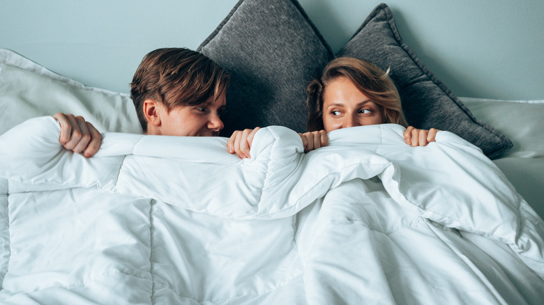 Couple under bedsheet after sex