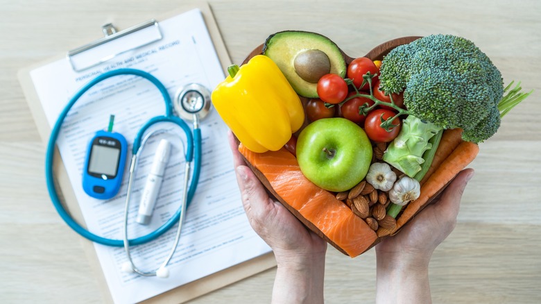 Person holding a heart-shaped plate filled with healthy food