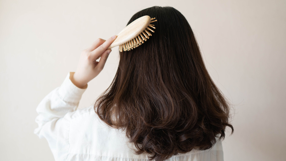 A woman brushes her hair from behind