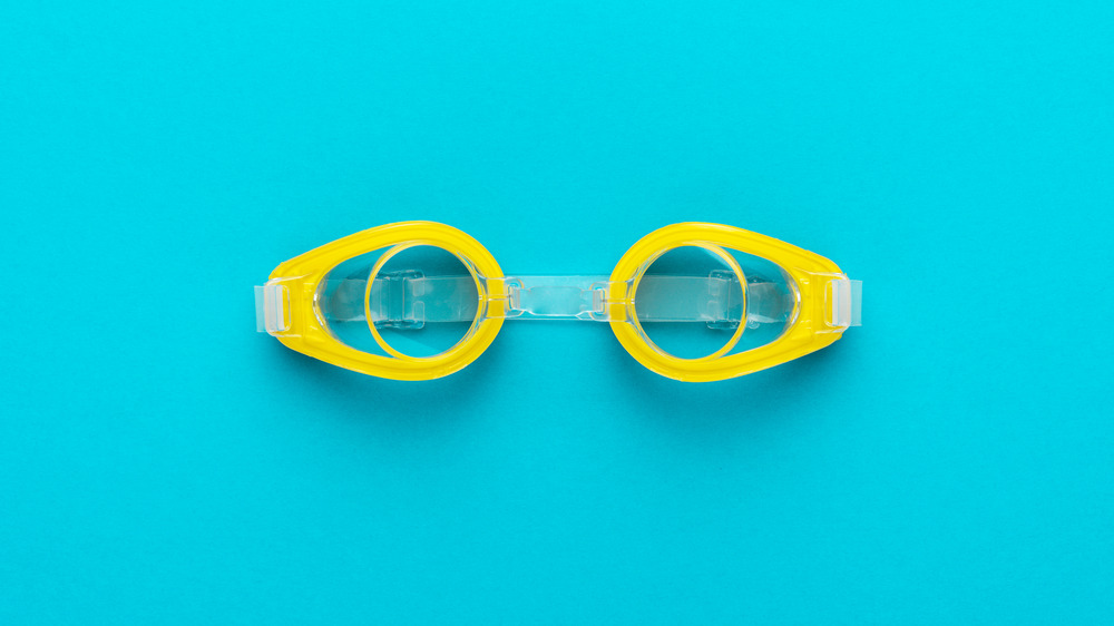 Yellow swimming goggles against blue background.