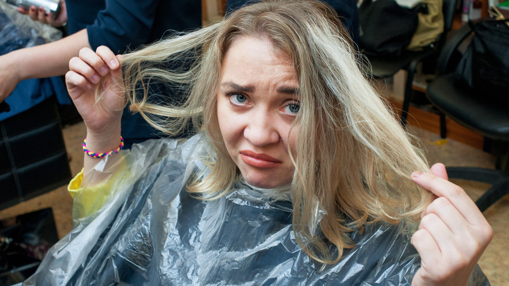 Unhappy woman with damaged hair at the hair dresser.