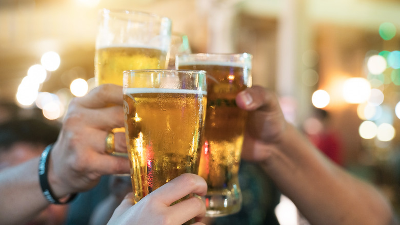 several people's hands toasting beer glasses