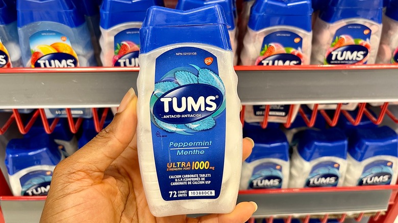 woman picking up tums from store shelf