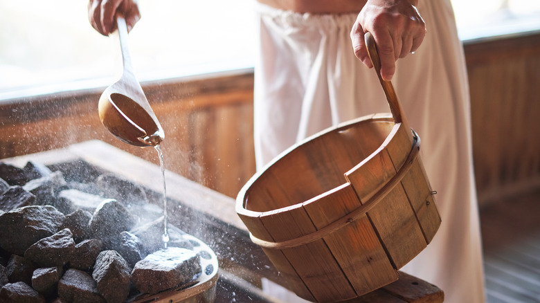 person in sauna steaming hot stones