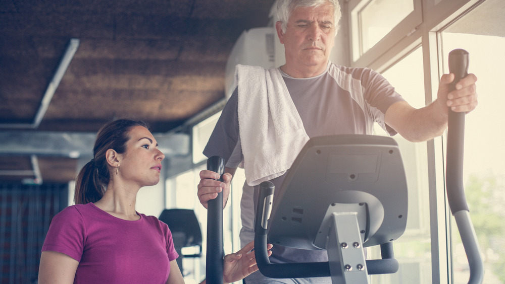 man on elliptical with trainer