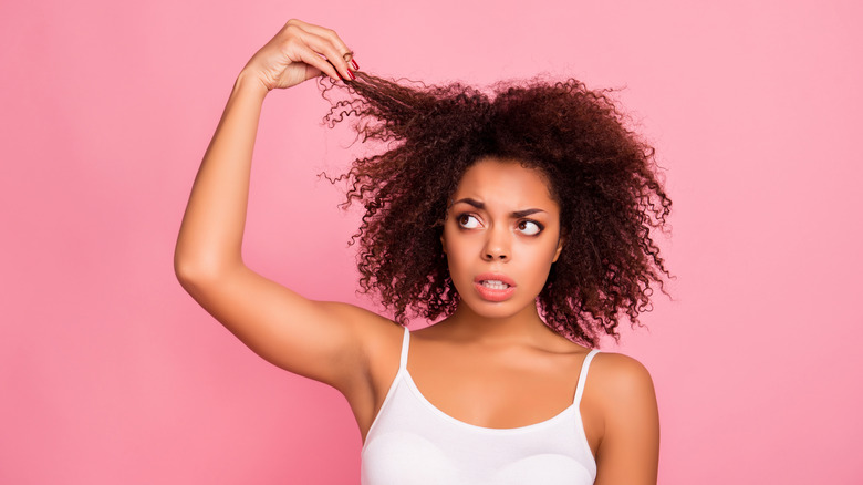 Young woman holding her hair against an all pink background 