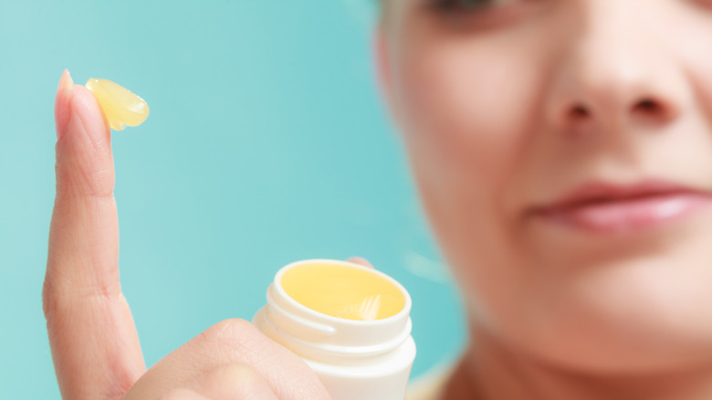 Closeup of woman holding a small jar of petroleum jelly