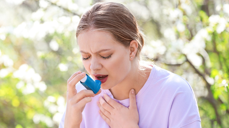Woman with asthma taking medication outside