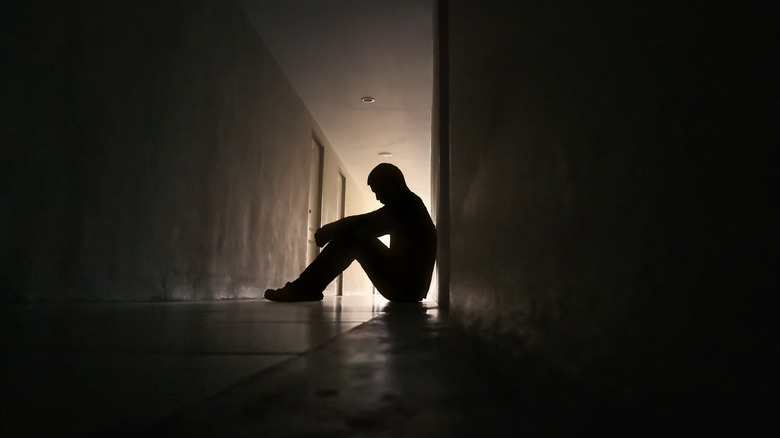 Silhouette of a depressed man sitting in a hallway