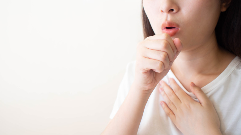 woman coughing, holding chest