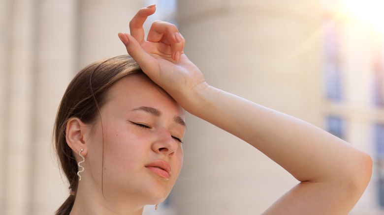 woman looking faint holding her hand on her head