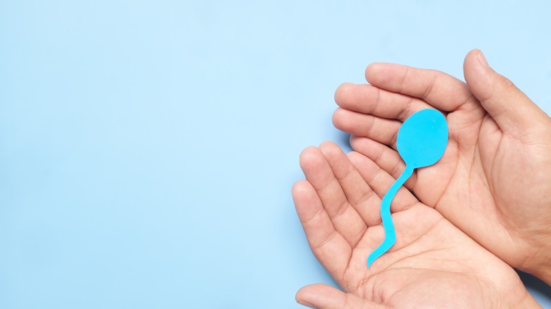 man holding a piece of paper shaped like a sperm 